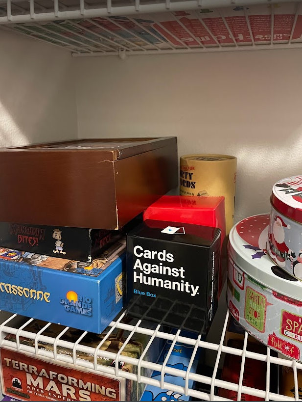 games on a self in a closet. from top to bottom:
column 1:
game of life
munchkin bites
Carcassonne
column 2:
dirty words
we're not strangers
cards against humanity blue box
column 3:
2 cookie tins with printed games
next shelf:
terraforming mars: ares expedition and killer bunnies are barely in frame