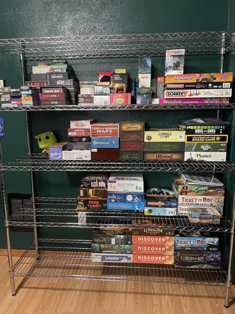 a shelf that has a variety of board games on it, however the shelf is half empty.